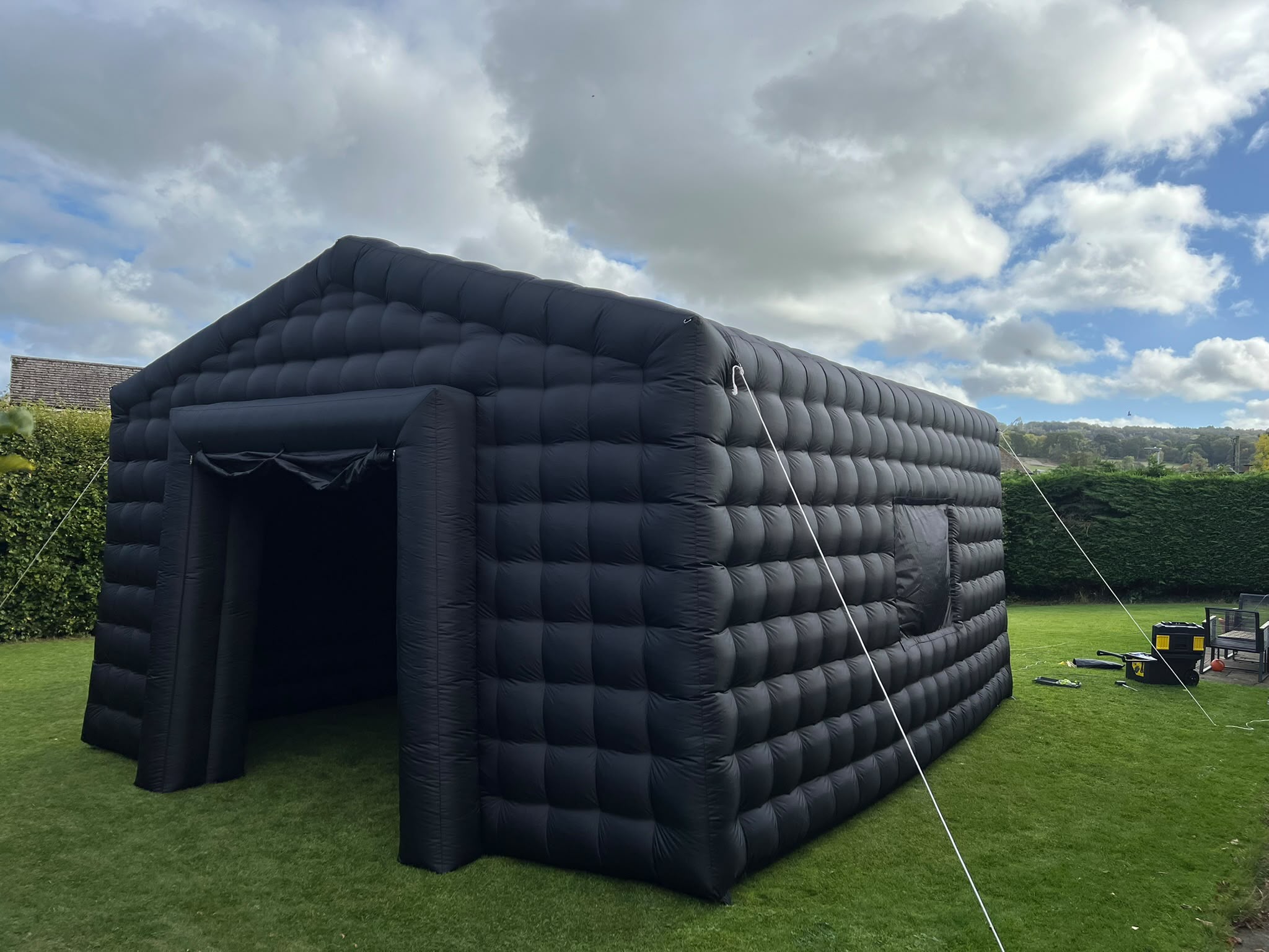 Black inflatable nightclub set up on a garden lawn