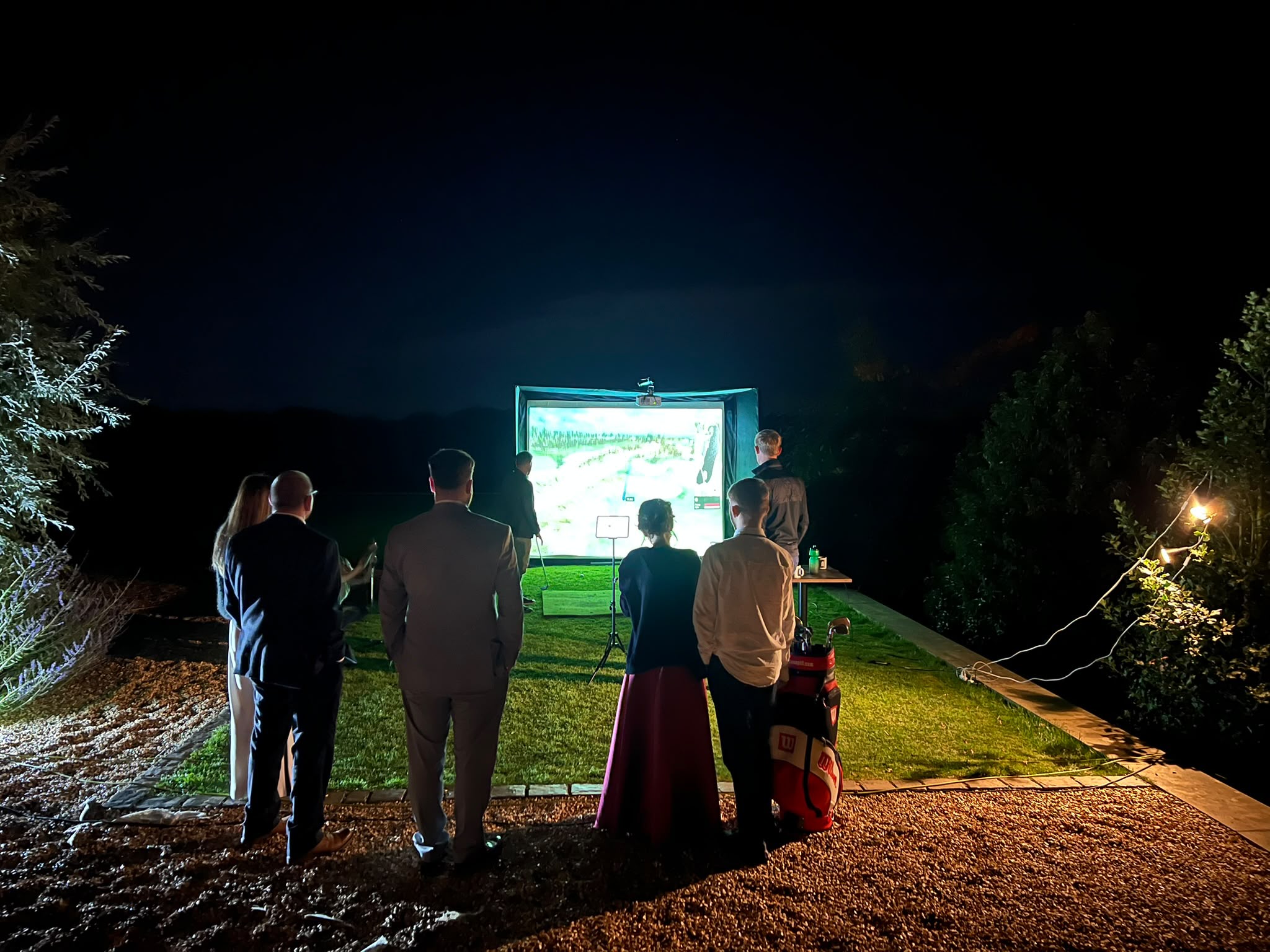 Guests gathered around the golf simulator for an evening competition