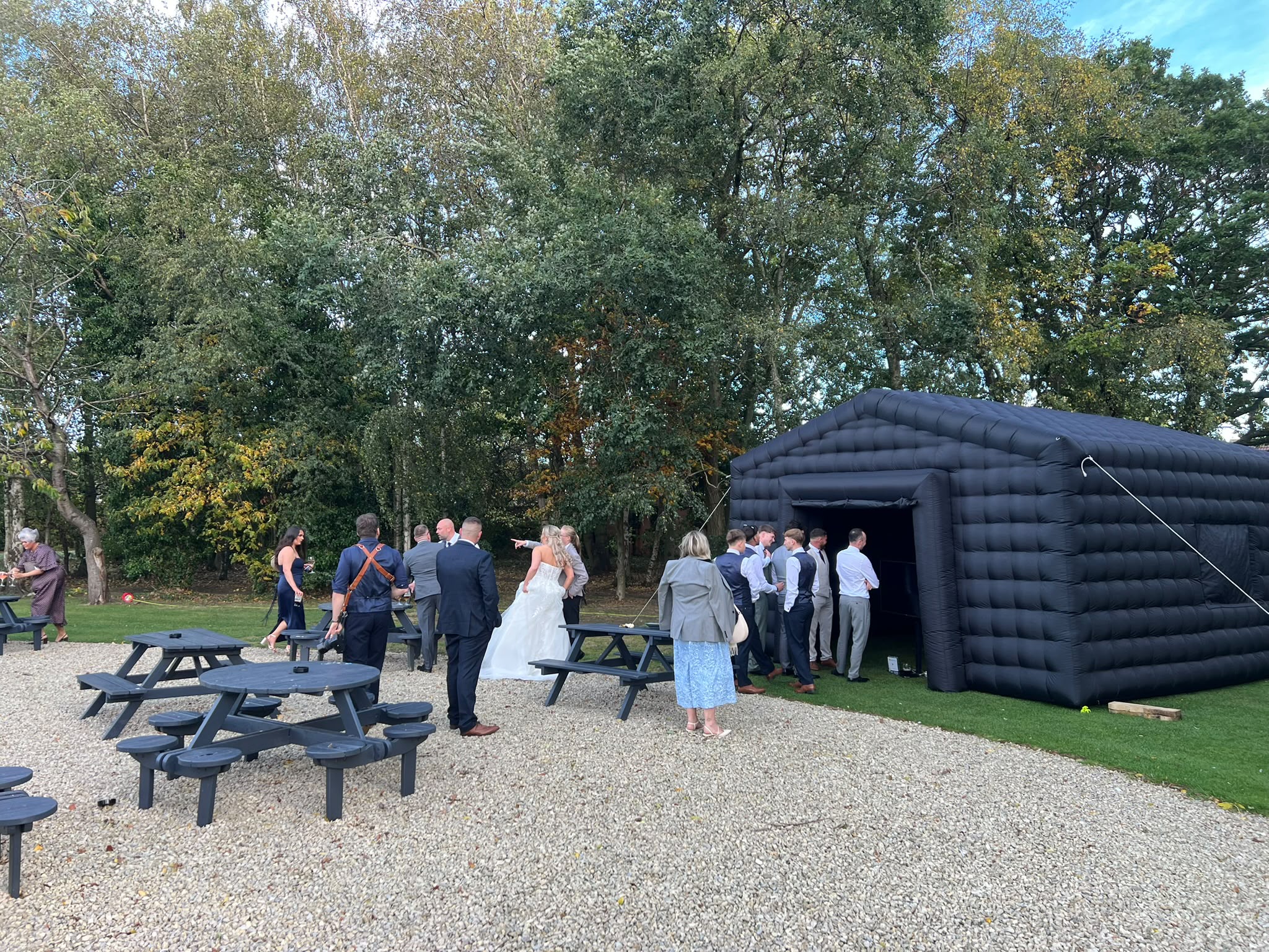 Wedding guests socialising outside the inflatable enclosure at a garden venue
