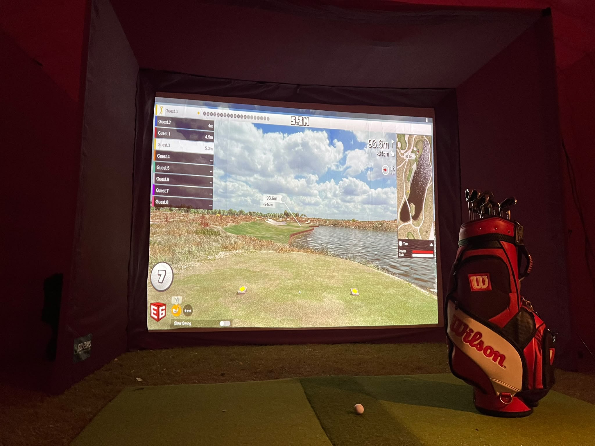 Golf simulator screen, hitting mat and clubs ready for a closest-to-the-pin competition